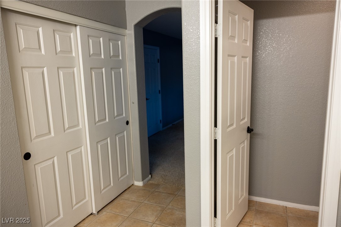 212 Malcolm Street Henderson, NV 89074 - Photo 33 of 47 Hall featuring arched walkways, light tile patterned floors, and a textured wall