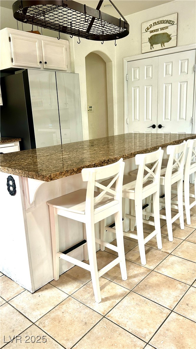 212 Malcolm Street Henderson, NV 89074 - Photo 39 of 47 Kitchen with a breakfast bar, white cabinets, ceramic tile patterned flooring, and dark stone counters