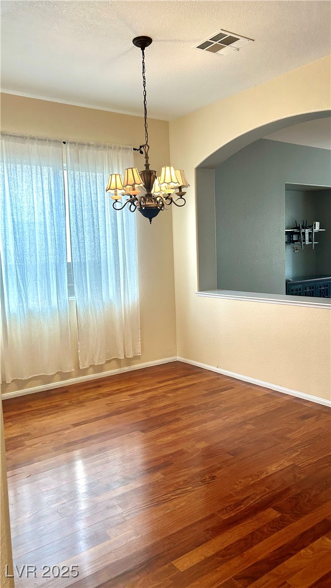 212 Malcolm Street Henderson, NV 89074 - Photo 41 of 47 Empty room with a chandelier, wood finished floors, a textured ceiling, and a textured wall