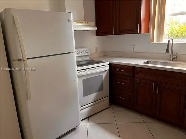 a kitchen with a sink a refrigerator and cabinets