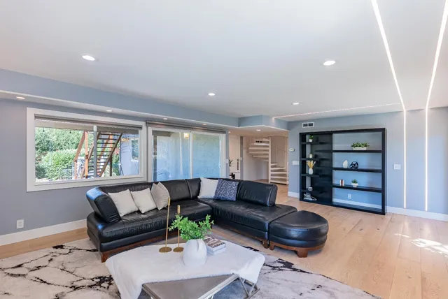 a view of a patio with couches chairs potted plants with wooden floor