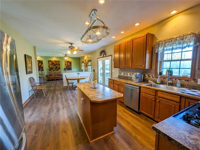 a kitchen with stainless steel appliances granite countertop wooden cabinets a sink dishwasher a stove and a refrigerator