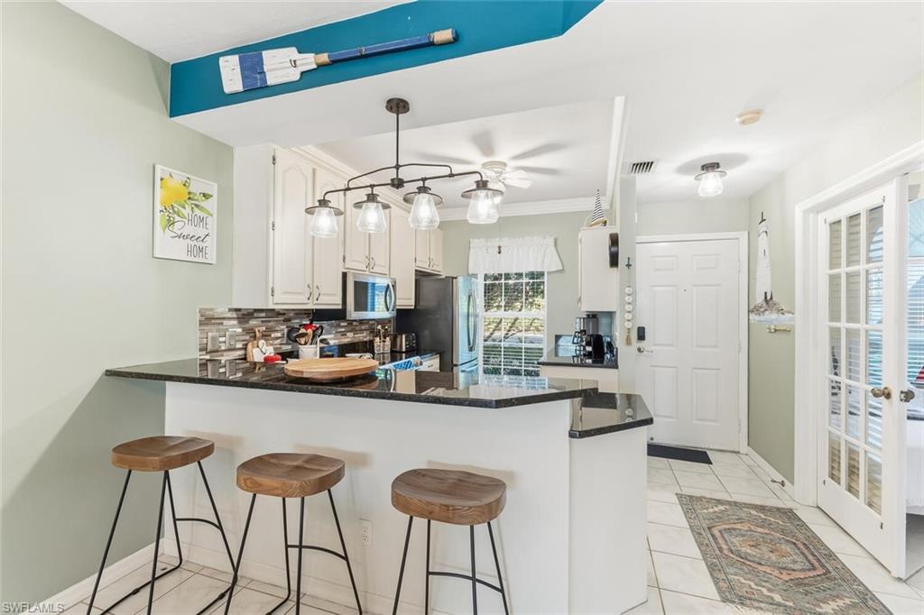 Undisclosed Address Naples, FL 34113 - Photo 4 of 24 a kitchen with stainless steel appliances kitchen island granite countertop a table and chairs in it