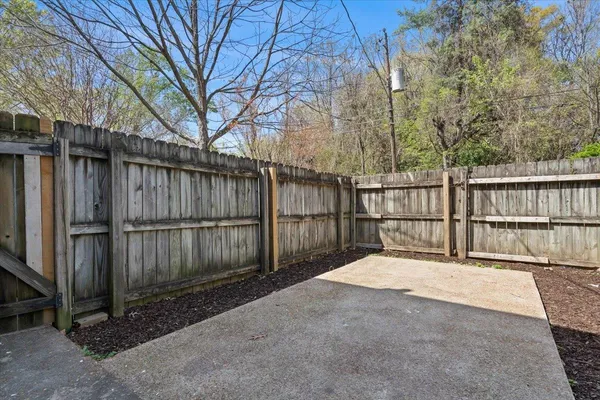 a view of backyard with large trees and wooden fence
