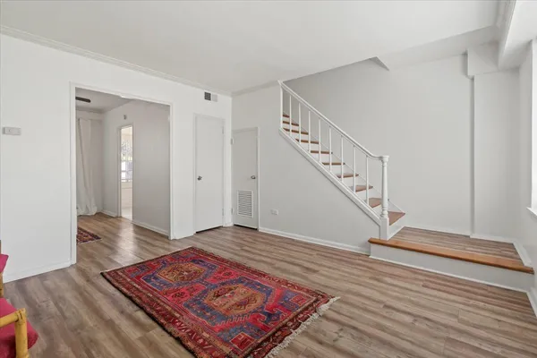 a view of an empty room with wooden floor and stairs