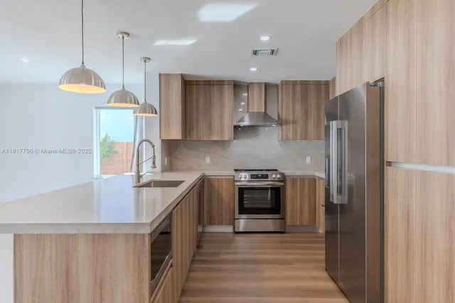 a kitchen with stainless steel appliances granite countertop a refrigerator a stove a sink and a refrigerator