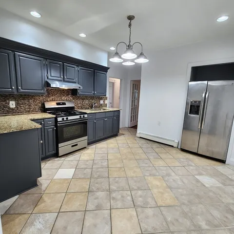 a kitchen with stainless steel appliances granite countertop a stove top oven a sink and a refrigerator