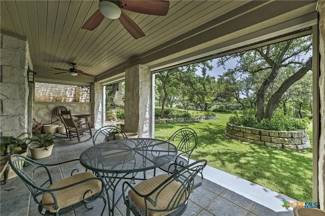 a view of a patio with table and chairs potted plants and floor to ceiling window