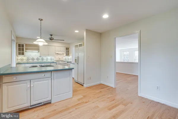 a kitchen with granite countertop a stove a sink and white cabinets with wooden floor