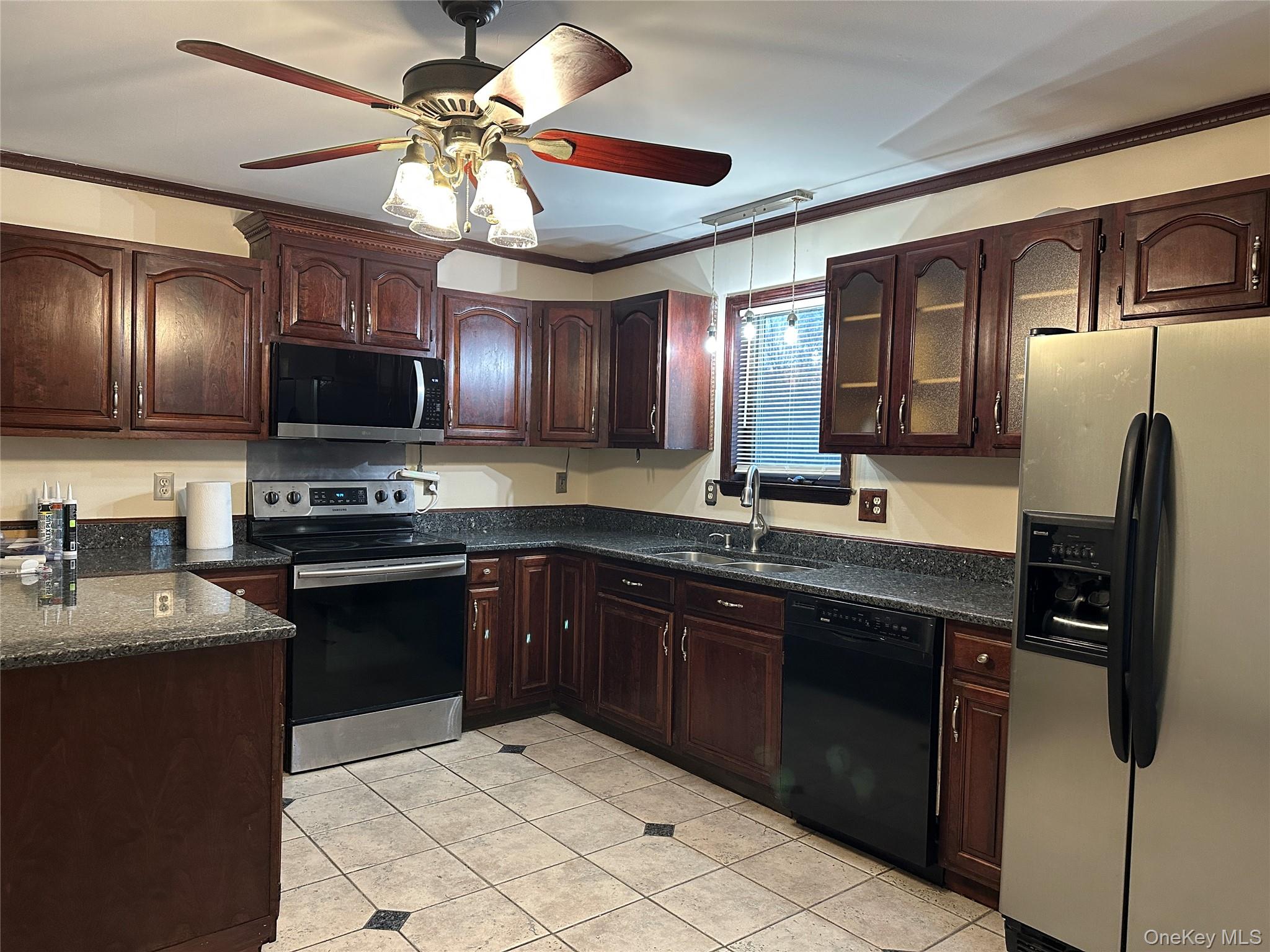 62 New Road Newburgh, NY 12550 - Photo 4 of 14 Kitchen featuring dark brown cabinets, ornamental molding, stainless steel appliances, light tile patterned floors, and ceiling fan