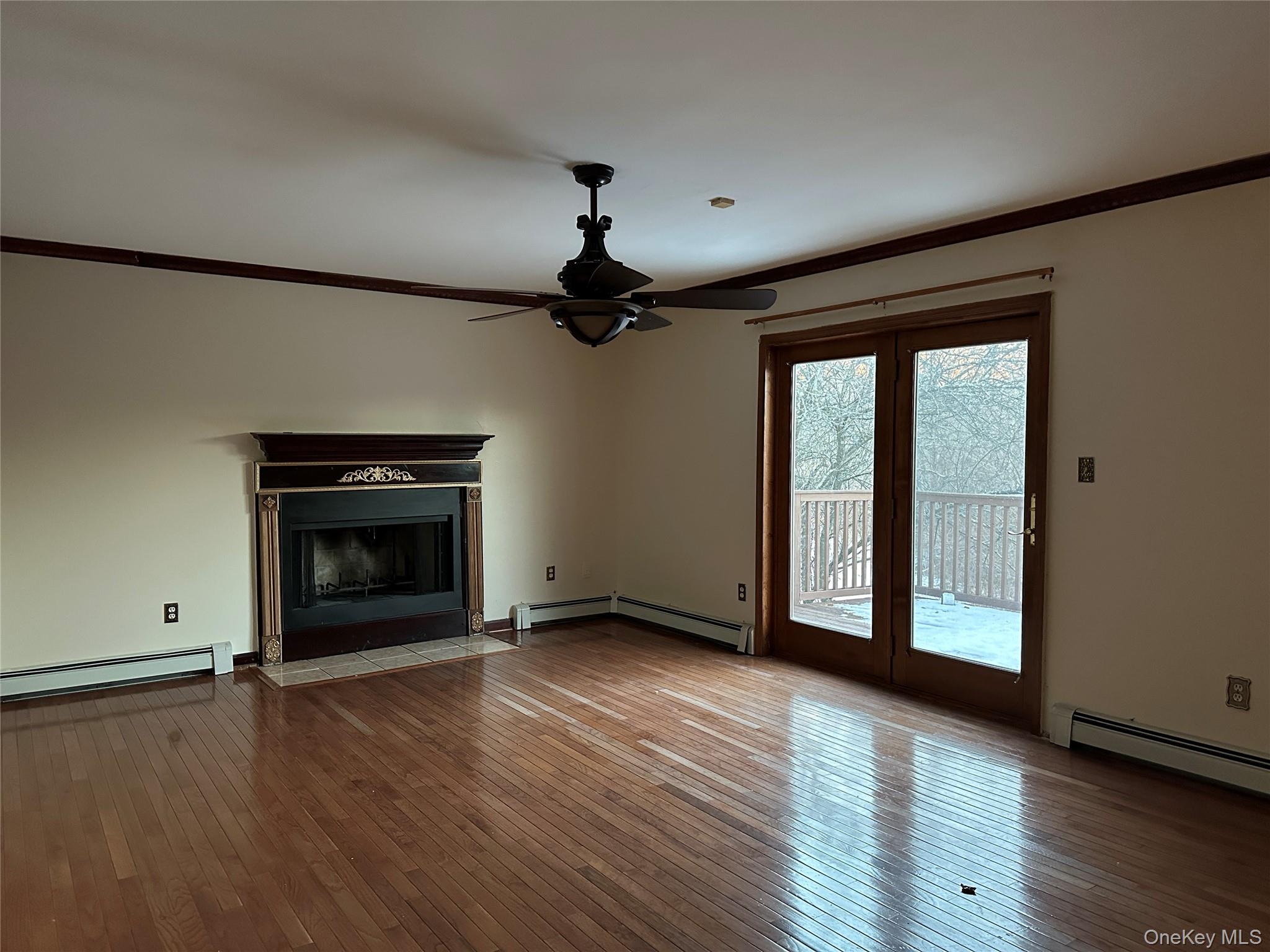 62 New Road Newburgh, NY 12550 - Photo 5 of 14 Unfurnished living room featuring ornamental molding, a fireplace with flush hearth, a baseboard radiator, hardwood / wood-style flooring, and ceiling fan