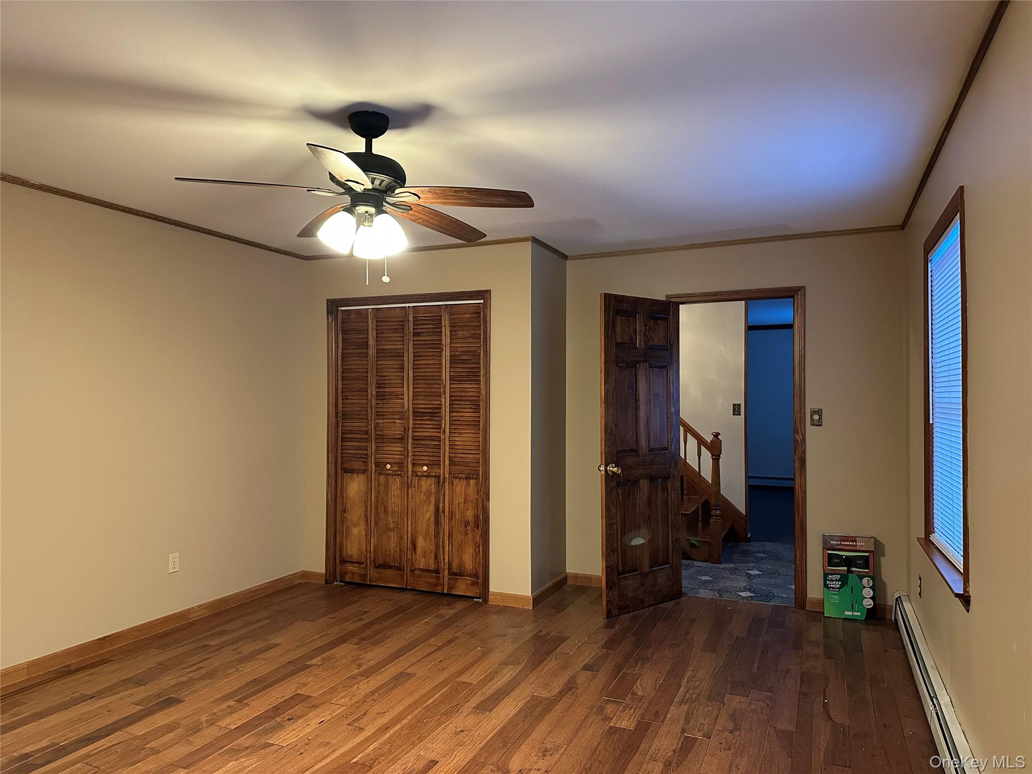 62 New Road Newburgh, NY 12550 - Photo 7 of 14 Unfurnished bedroom with baseboard heating, dark wood-style flooring, ceiling fan, a closet, and ornamental molding