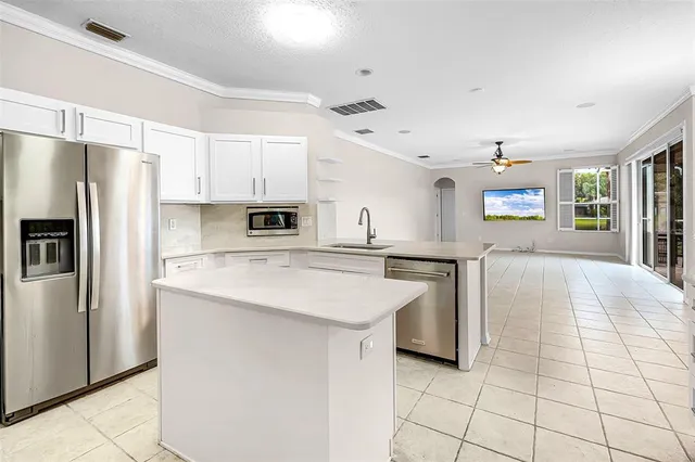 a kitchen with kitchen island a counter top space a sink stainless steel appliances and cabinets