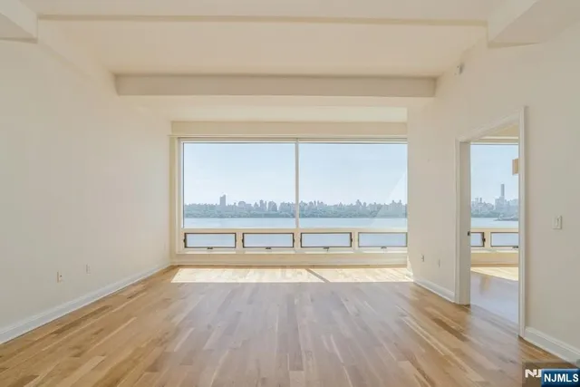 an empty room with wooden floor and a floor to ceiling window