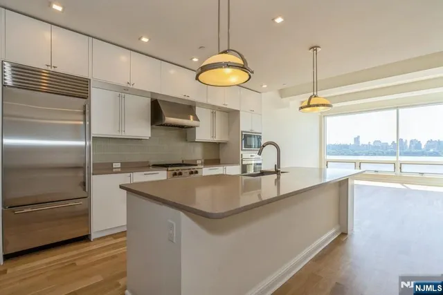 a kitchen with stainless steel appliances granite countertop a sink a stove and a refrigerator
