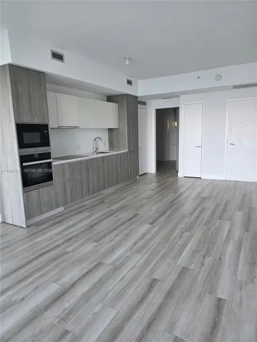 a view of a kitchen with wooden floor and electronic appliances