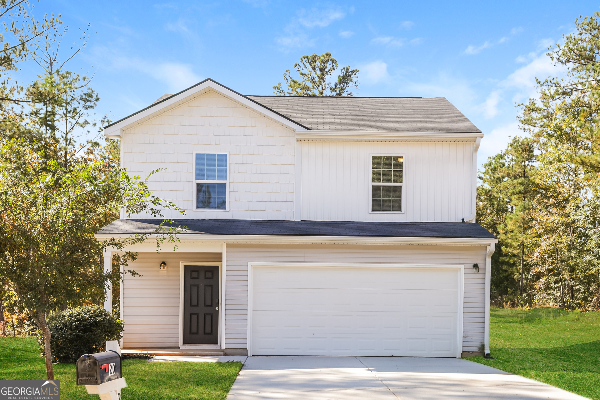 a view of a white house next to a yard with big trees