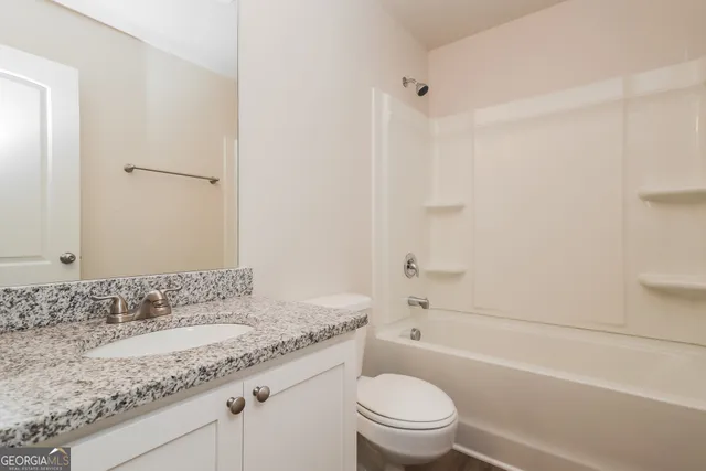 a bathroom with a granite countertop sink a toilet and shower