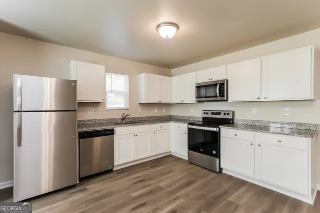 a kitchen with granite countertop white cabinets and stainless steel appliances