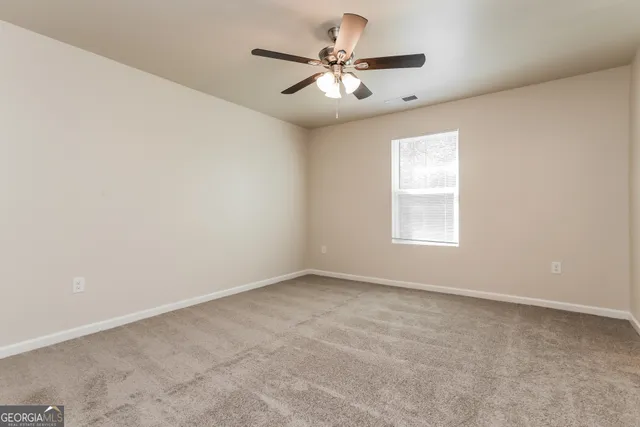an empty room with windows and ceiling fan