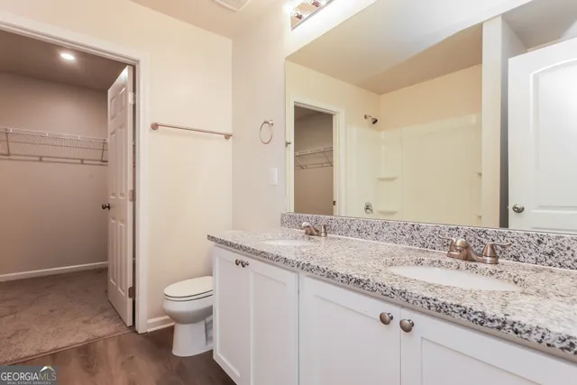 a bathroom with a granite countertop sink a toilet and a large mirror