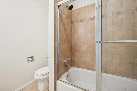 a bathroom with a granite countertop bathtub shower and toilet