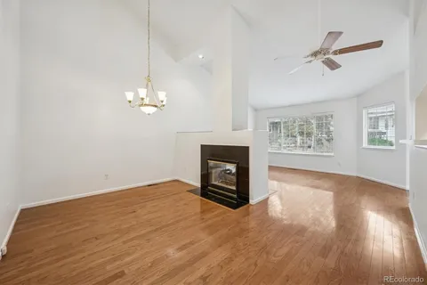 a view of a livingroom with a fireplace a ceiling fan and wooden floor