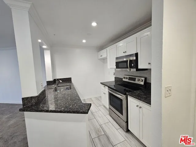 a kitchen with granite countertop a stove sink and microwave