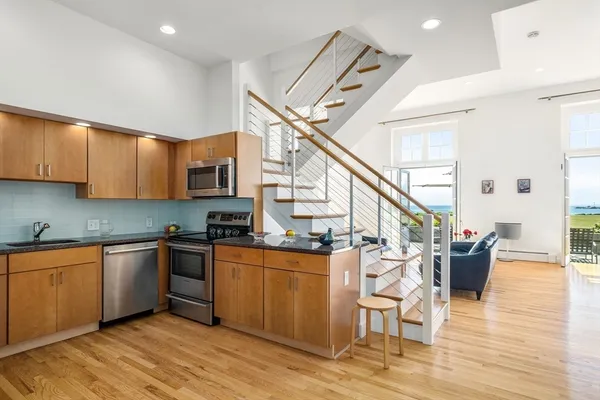 a open kitchen with stainless steel appliances granite countertop a stove and a wooden floors