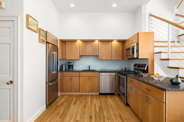 a kitchen with stainless steel appliances granite countertop a refrigerator a sink dishwasher a stove with wooden cabinets and floor