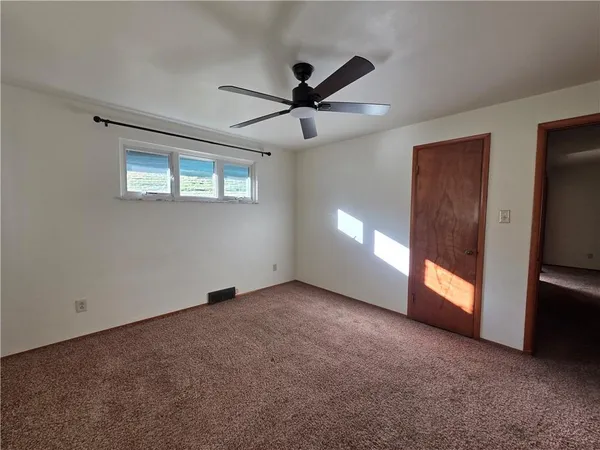 a view of an empty room with a window and a kitchen