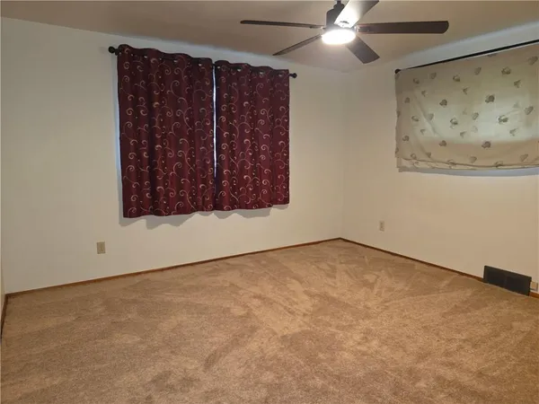 an empty room with a fan & a window