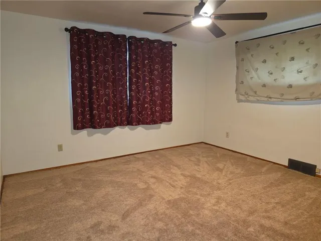 an empty room with a fan & a window