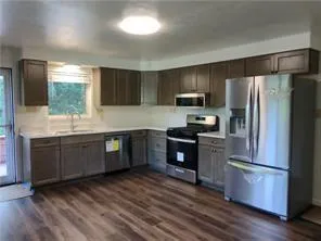 a kitchen with granite countertop a refrigerator stove top oven and sink