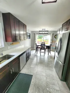 a dining hall with granite countertop a refrigerator a stove top oven a sink and dishwasher