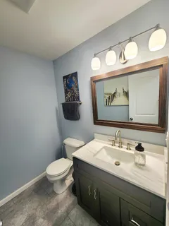 a bathroom with a toilet sink vanity and mirror