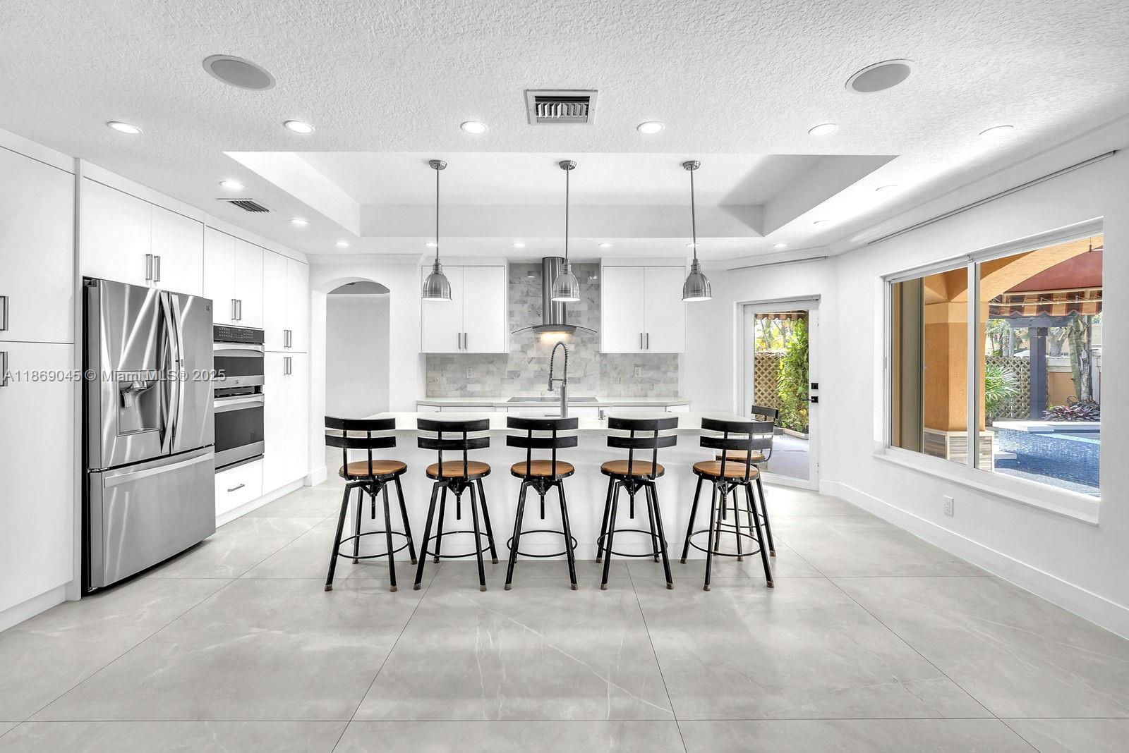 15244 Southwest 29th Terrace Miami, FL 33185 - Photo 14 of 74 a kitchen with stainless steel appliances kitchen island granite countertop a table chairs stove and refrigerator