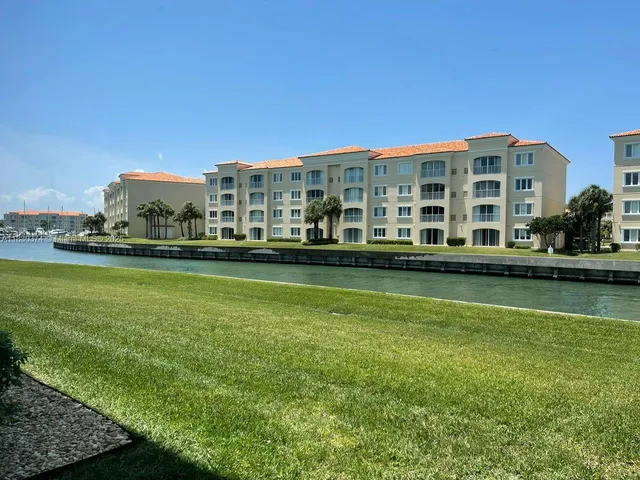 a view of a building with a big yard and large trees