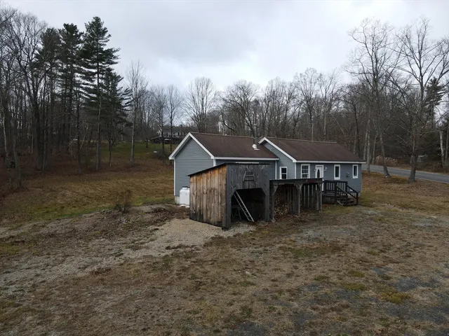 a view of a house with large trees and a wooden fence