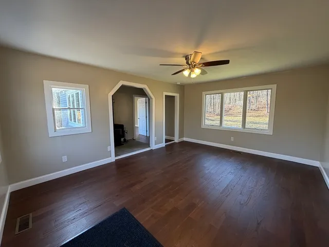 a view of an empty room with a window and wooden floor