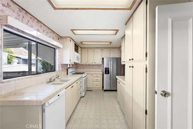a large white kitchen with a stove a refrigerator a sink and dishwasher with a dining table