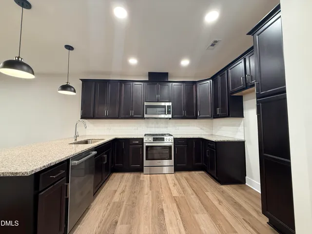 a kitchen with stainless steel appliances granite countertop a stove a sink and a microwave