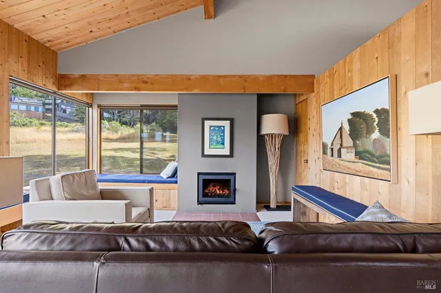 a living room with furniture floor to ceiling window and a flat screen tv