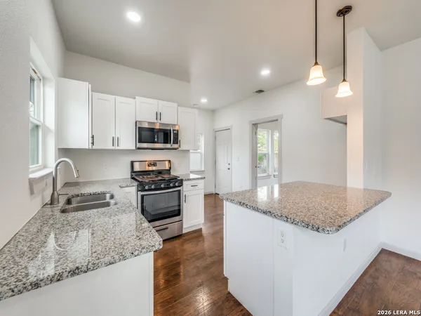 a kitchen with granite countertop a sink a counter top space appliances and cabinets