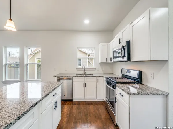 a kitchen with granite countertop kitchen island wooden cabinets stainless steel appliances a sink and a large window