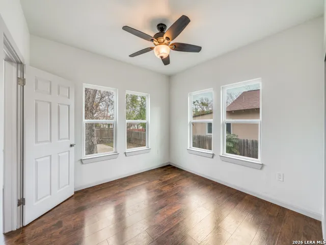 a view of an empty room with wooden floor and a window
