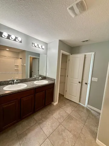a spacious bathroom with a granite countertop sink a mirror and a bathtub