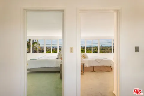 a bedroom with a bed a table and windows