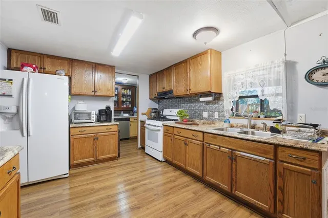 a kitchen with stainless steel appliances granite countertop a sink a stove cabinets and wooden floor