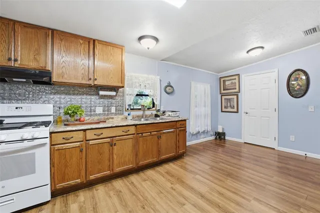 a kitchen with a sink and a stove with wooden floor